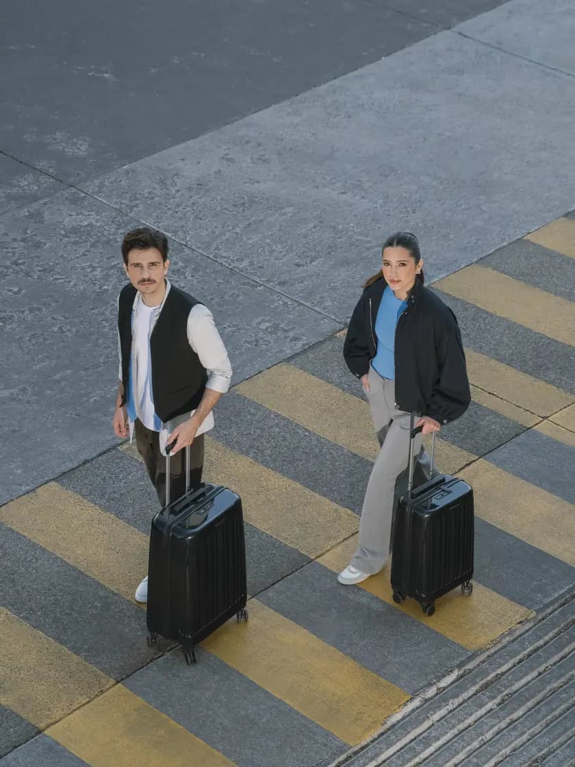 Dos personas cruzando la calle con maletas de mano Chenson negras