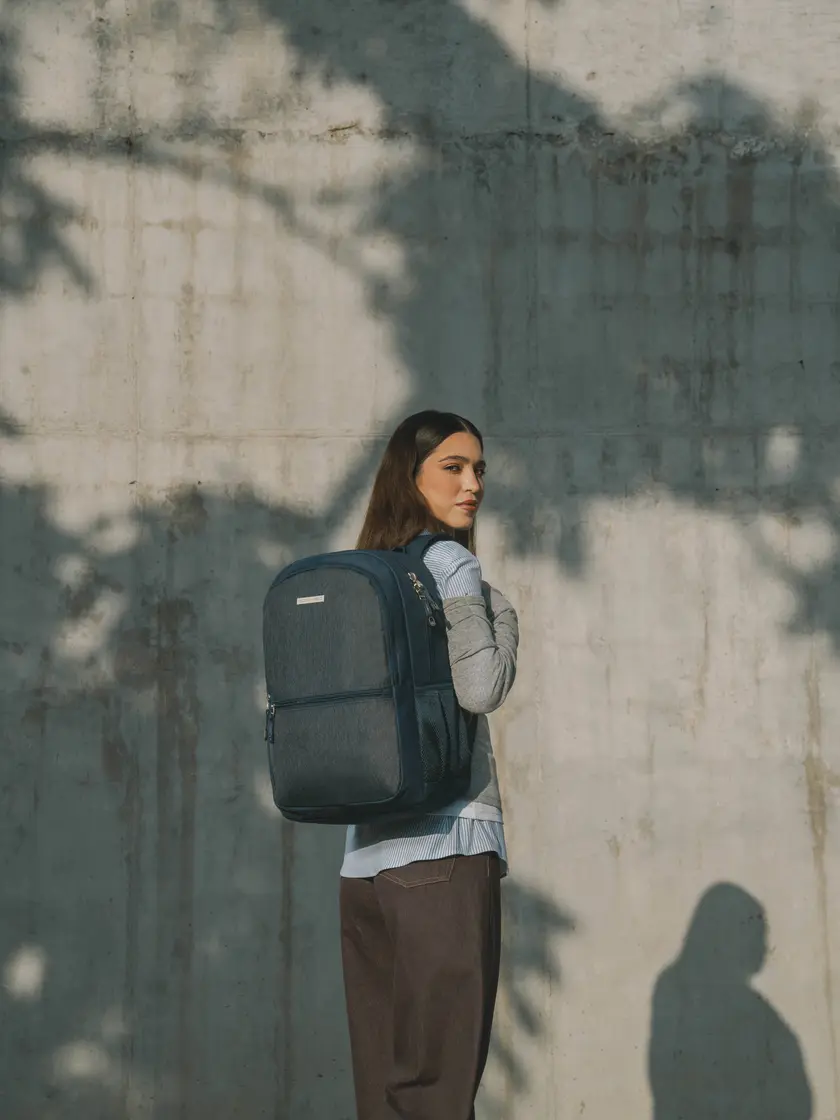 Mujer recargada en un muro con una mochila Chenson gris para laptop